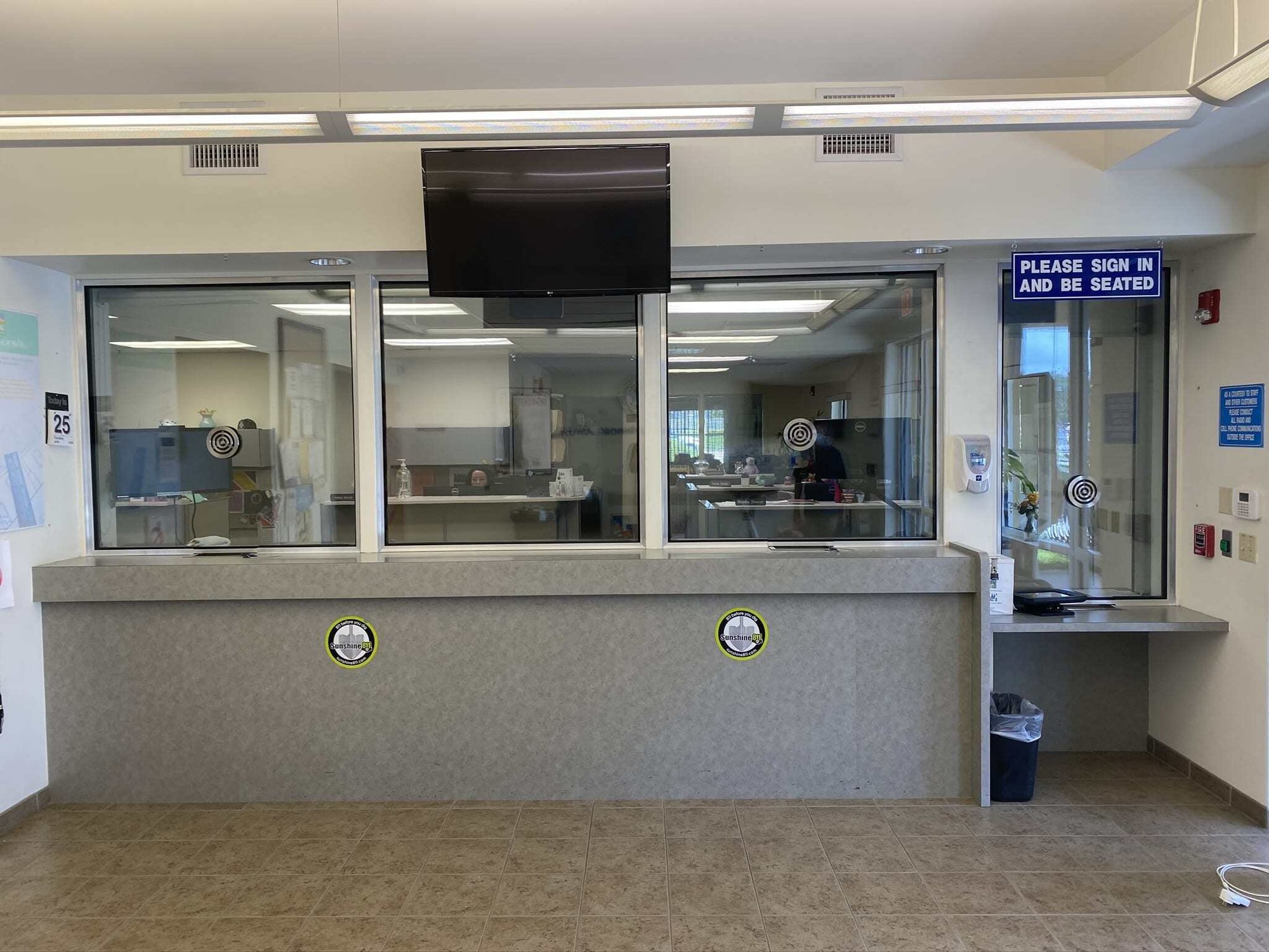 Ballistic glazing installed at a commercial reception lobby, with stickers marking where rounds were stopped during field testing.